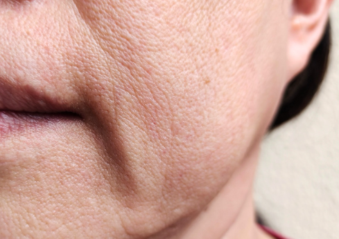 A close-up of a woman's face showing wrinkles, wearing a bright red shirt, conveying wisdom and experience.